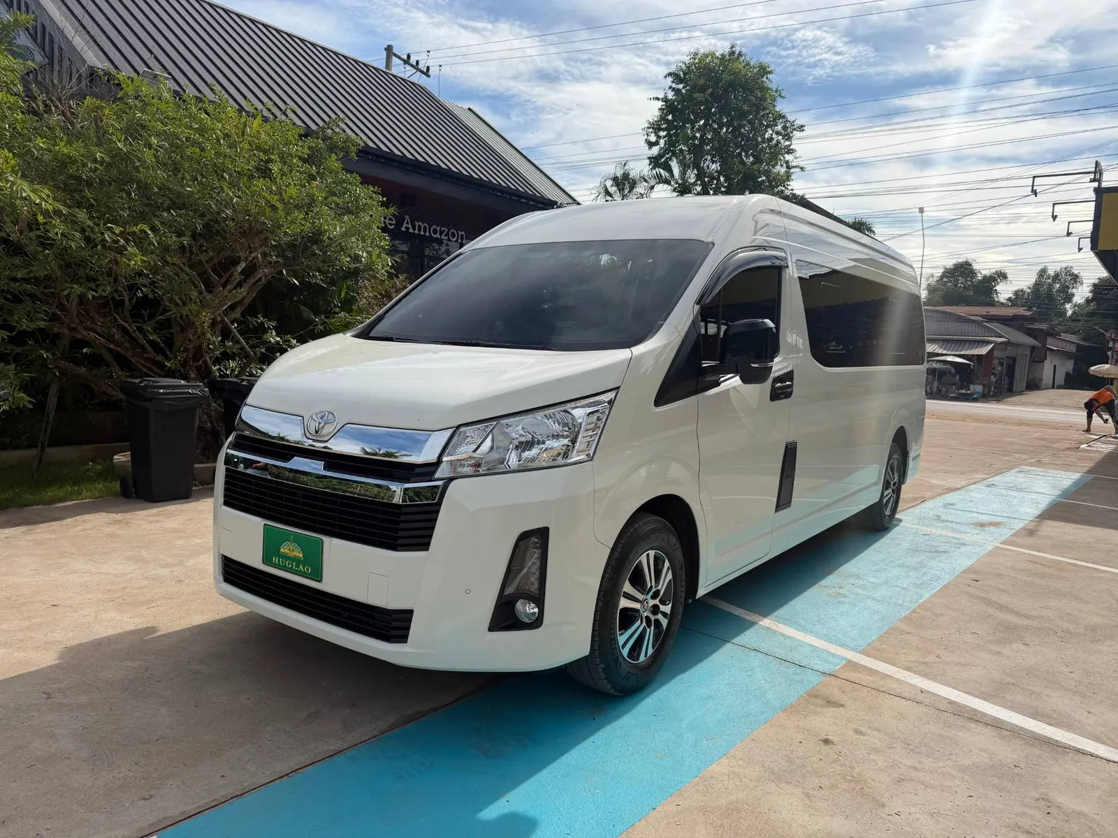 รถตู้ Toyota Hiace หลังคาสูงสีขาวของทีม HUGLAO มุมด้านหน้า